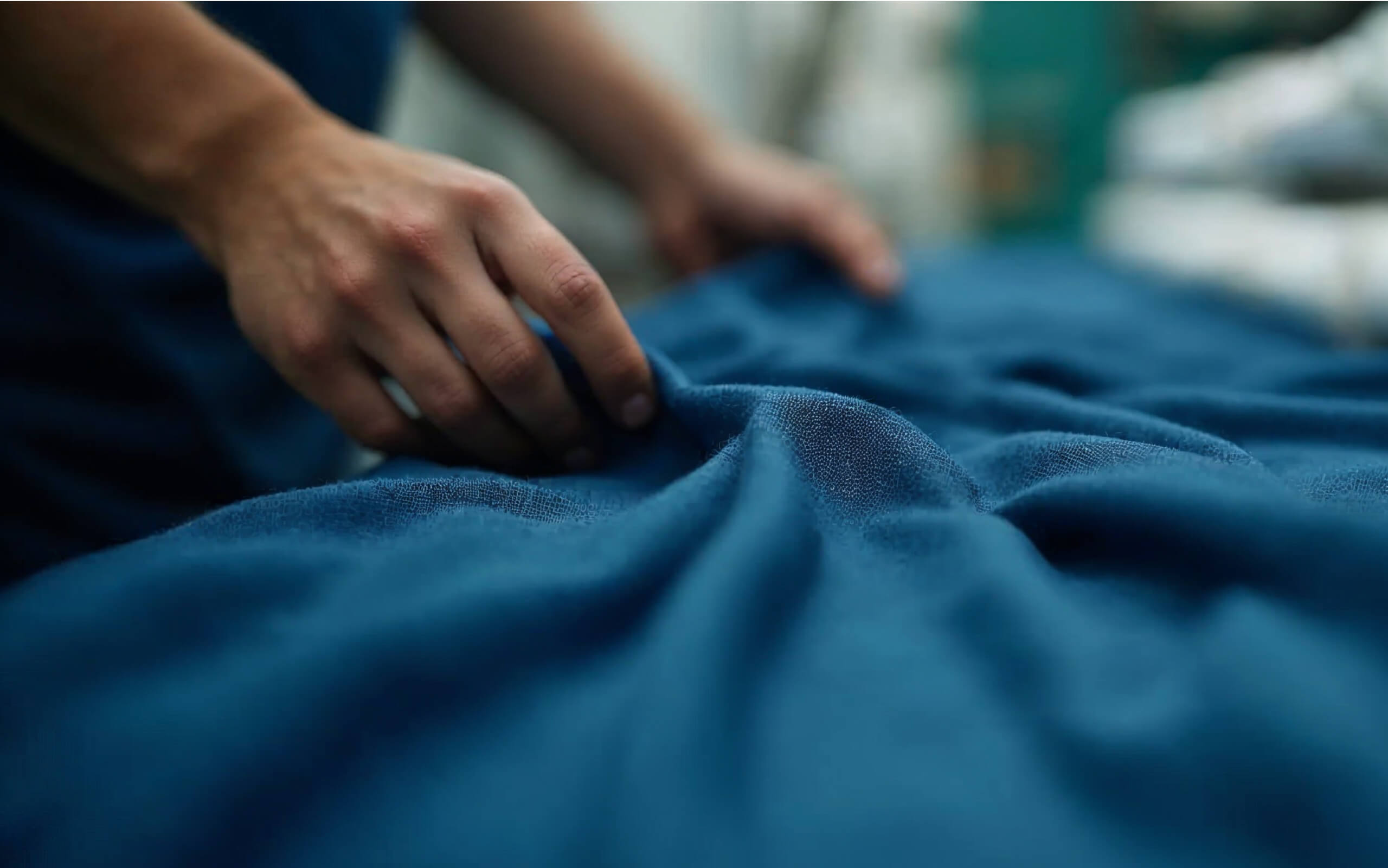 Hands adjusting blue fabric, focusing on texture.
